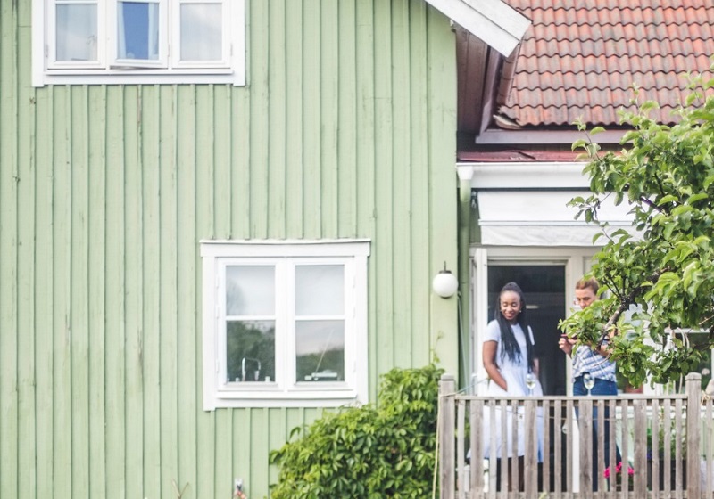 Par pratar på veranda utanför grönt hus