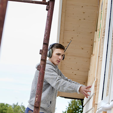 Hantverkare på byggnadsställning lägger plankor på hus