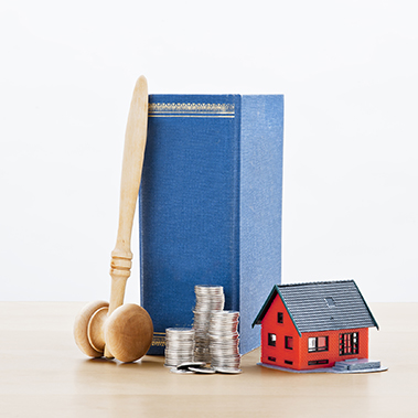 Lagbok och klubba tilssamans med rött miniatyrhus och mynt