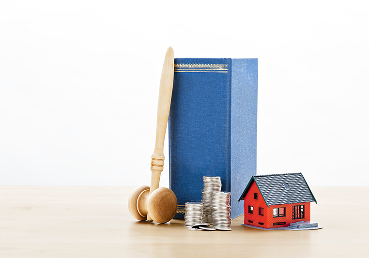 Lagbok och klubba tilsammans med rött miniatyrhus och mynt