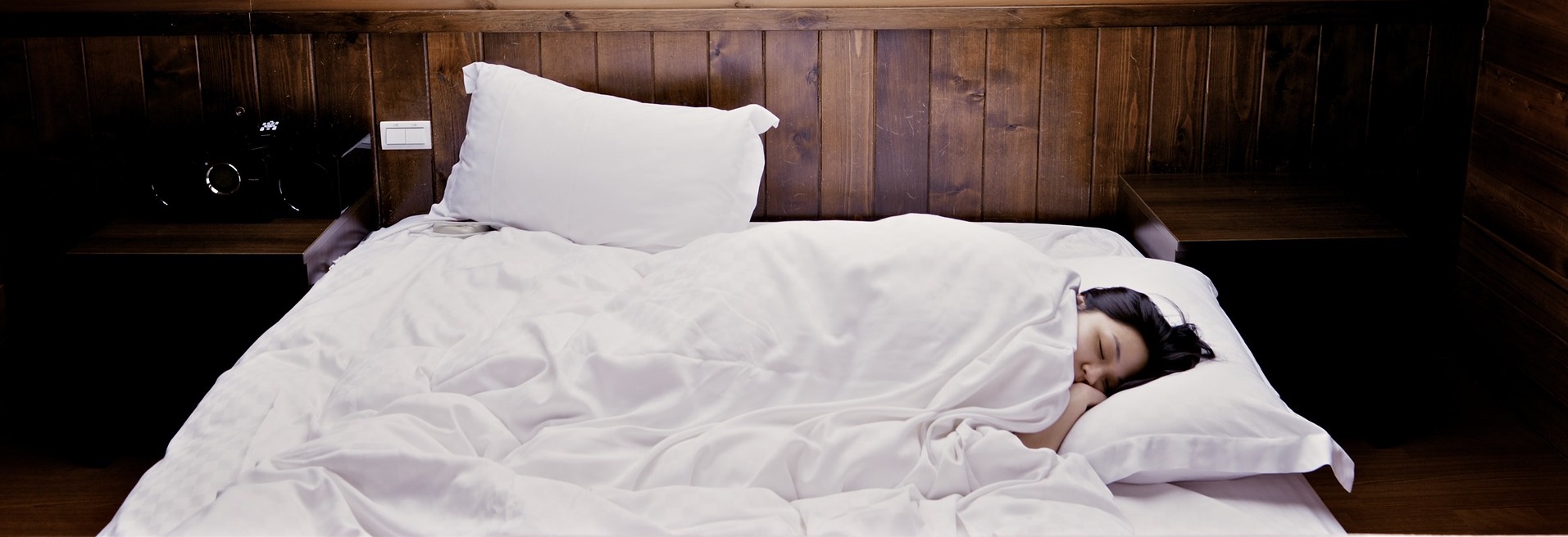 Kvinna sover i säng under snedtak med fönster