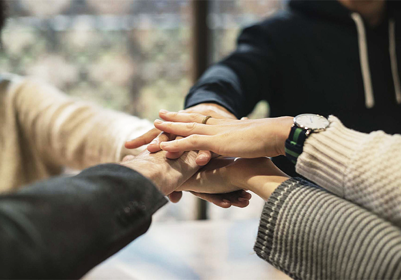 Människor i ring sträcker sina händer mot varandra