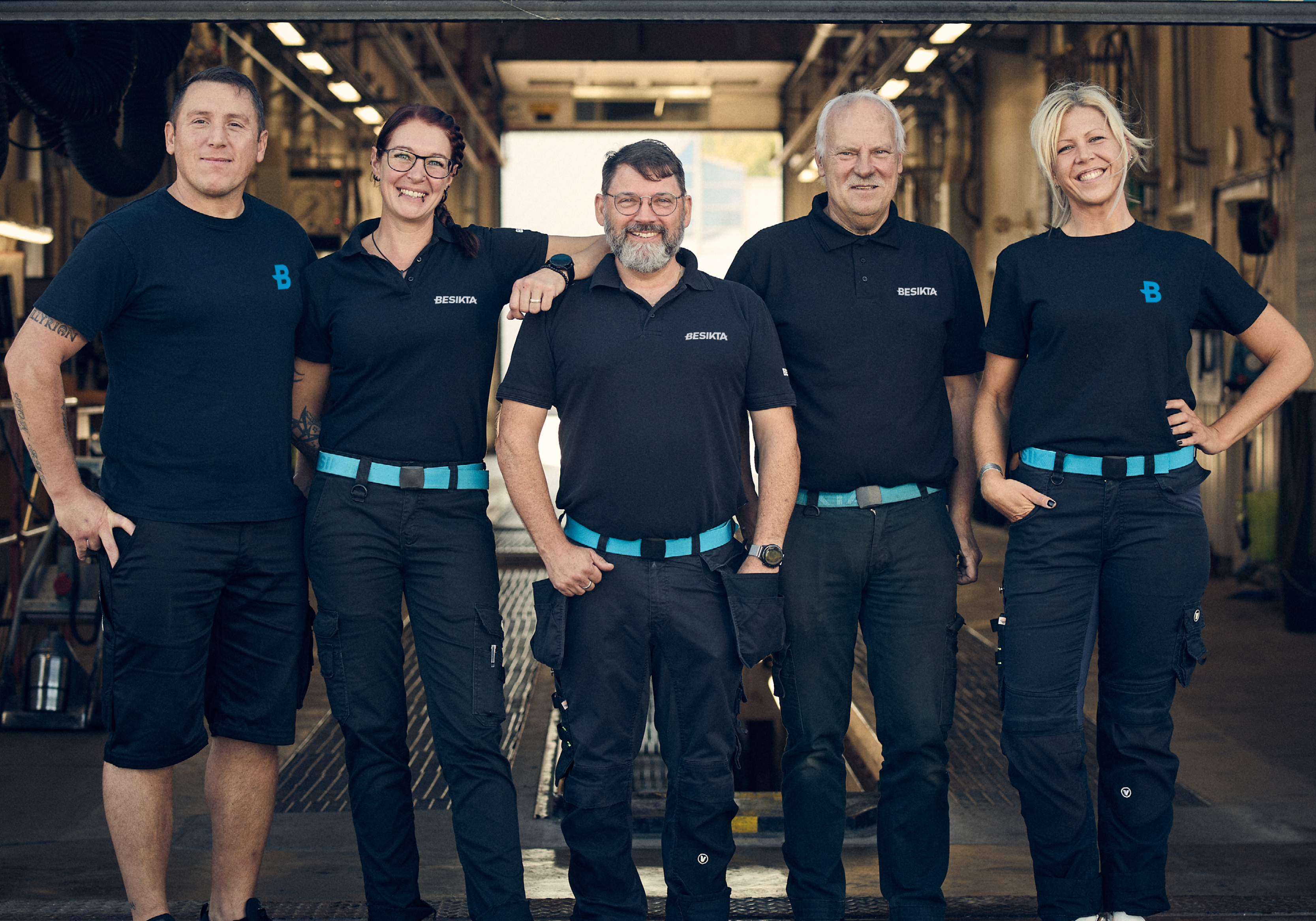 fem personer som står bredvid varandra inne på en besiktningsstation