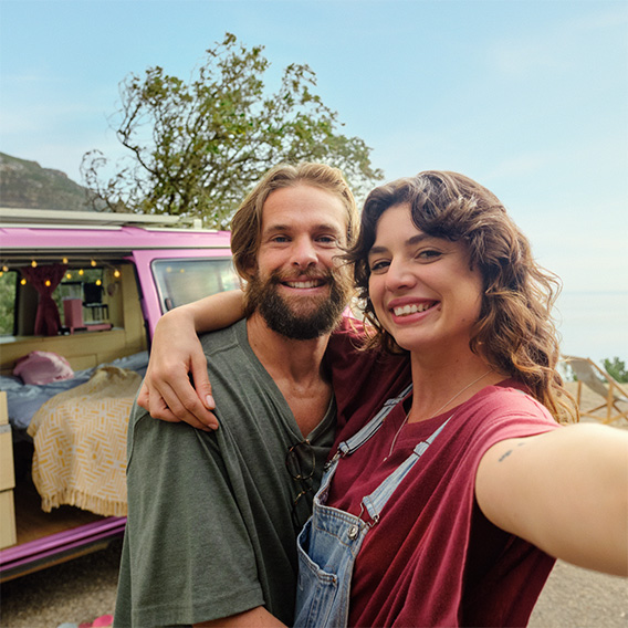 Kvinna och man tar bild på sig själva vid en husbil