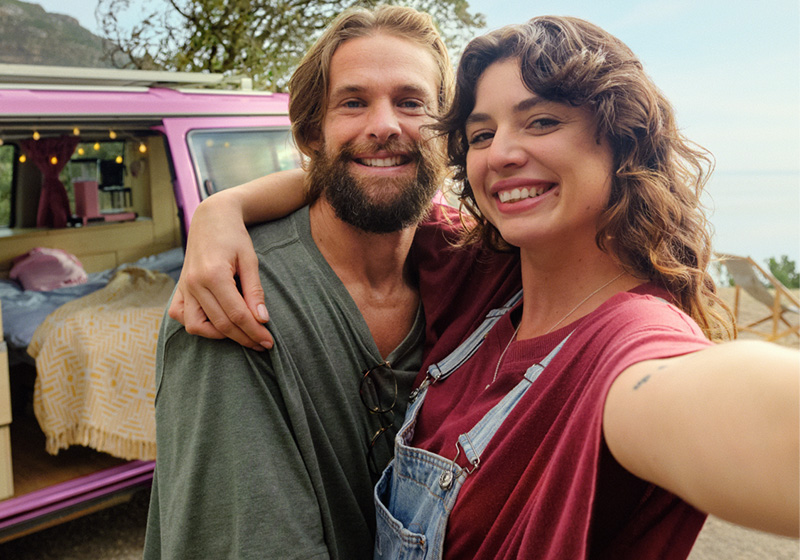 Kvinna och man tar bild på sig själva vid en husbil