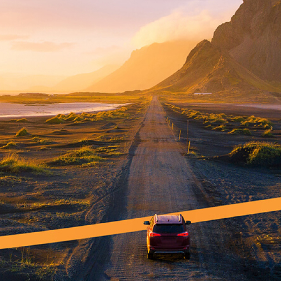 Bil på landsväg i vackert landskap i solnedgång