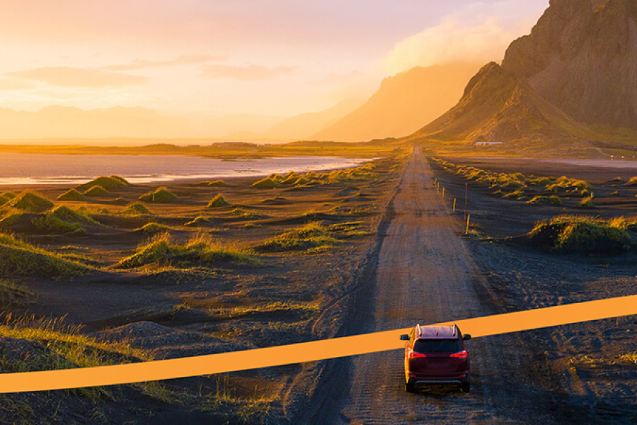 Bil på landsväg i vackert landskap i solnedgång