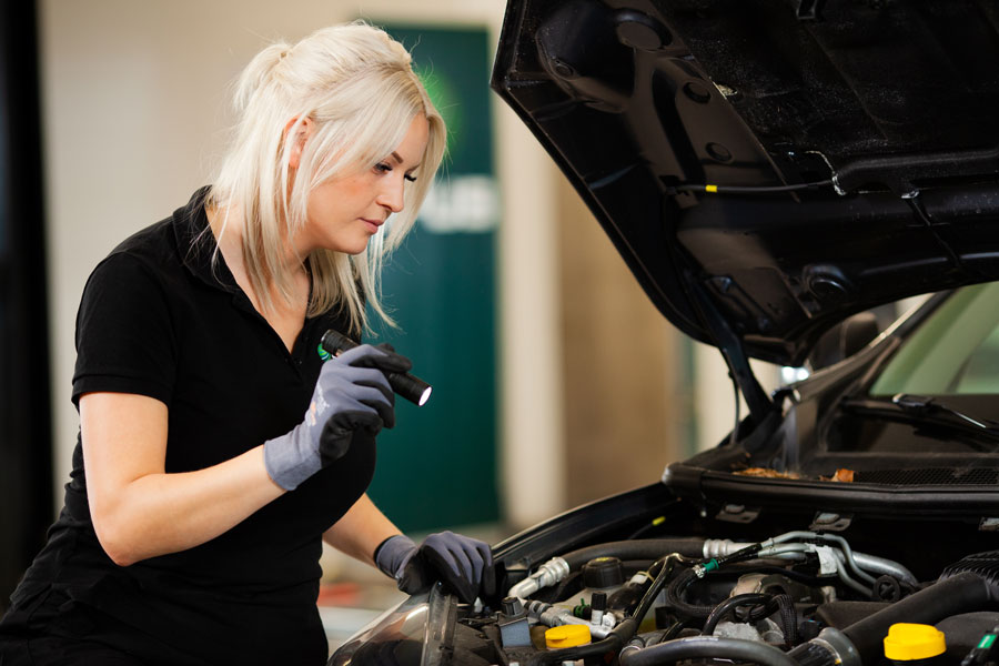 Mekaniker lyser med ficklampa i motorhuven