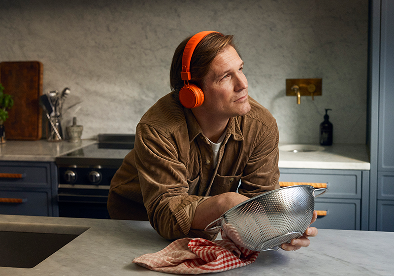 Man som står i köket och torka disk och lyssnar på ljudbok
